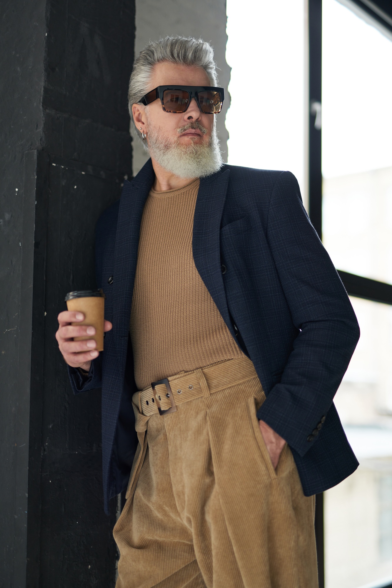 Handsome stylish middle aged man in business casual wear and sunglasses holding a cup of coffee